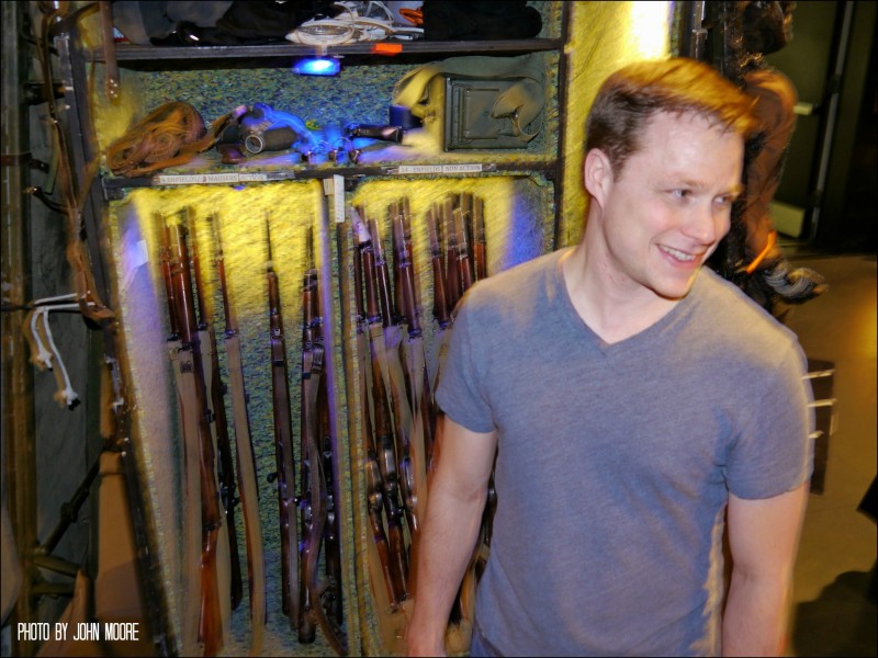 Mat Hostetler, who plays Veterinary Officer Martin, among other roles, shows off his guns backstage at the Buell Theatre. Photo by John Moore.  