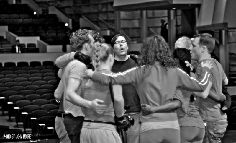 The cast circles up for a vocal warmup onstage at the Buell Theatre moments before the audience is allowed in. Photo by John Moore.  