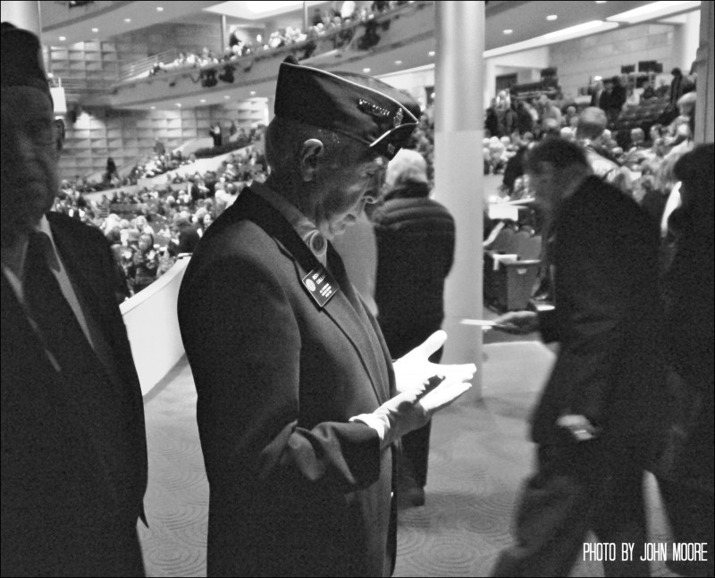 Veteran Richard Callan takes a moment to check his glove moments before the presentation of the Color Guard. Photo by John Moore.  