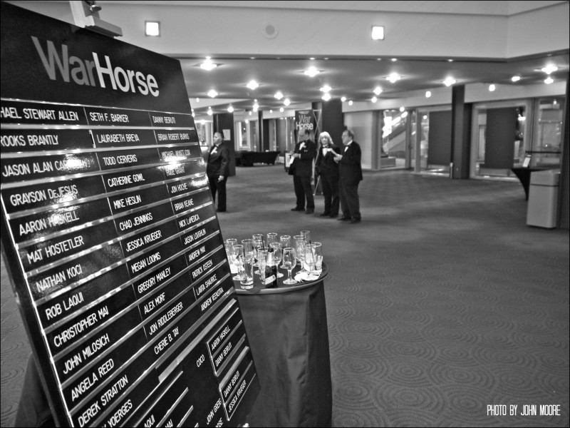 Once the show begins, the volunteer ushers gather around a closed-circuit television in the lobby to watch the opening scene. Photo by John Moore. 